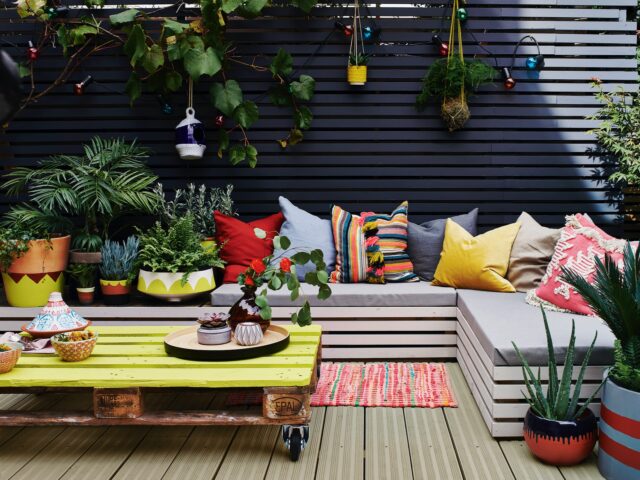 Charcoal painted garden fence with bench seating and hanging pots