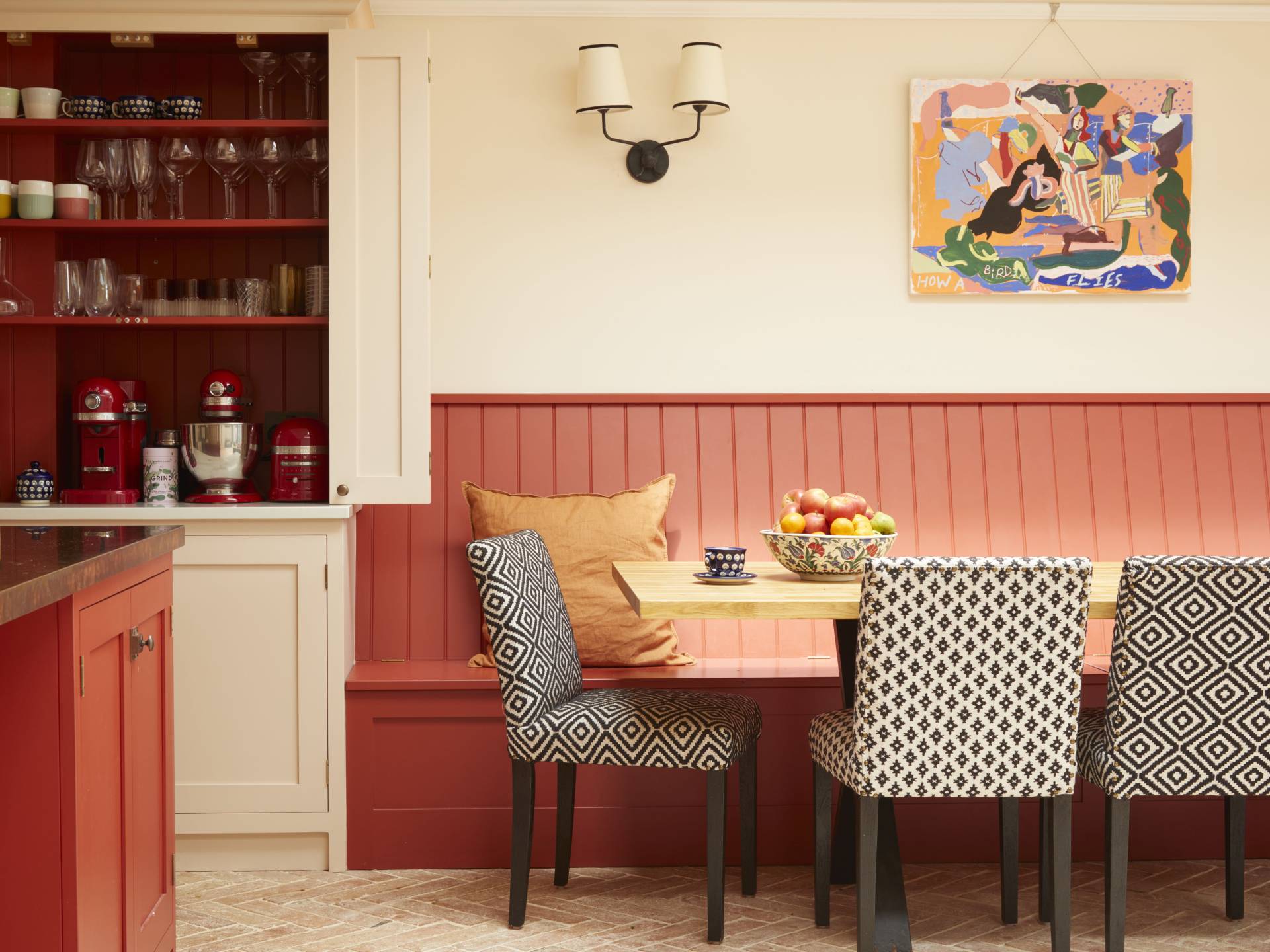 Off white kitchen with coral banquette dining area
