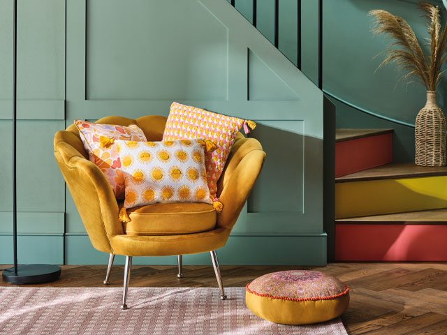 colourful home decor: hallway with sage green panelling plus mustard accent chair and painted stair risers