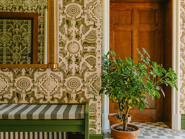 Patterned wallpaper hallway with side bench and foliage