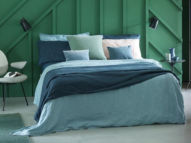 woman sleeping in a bed with a calming cloud wall painting above bed copyarthborn paints hobby wood in calming bedroom scheme - goodhomesmagazine.com