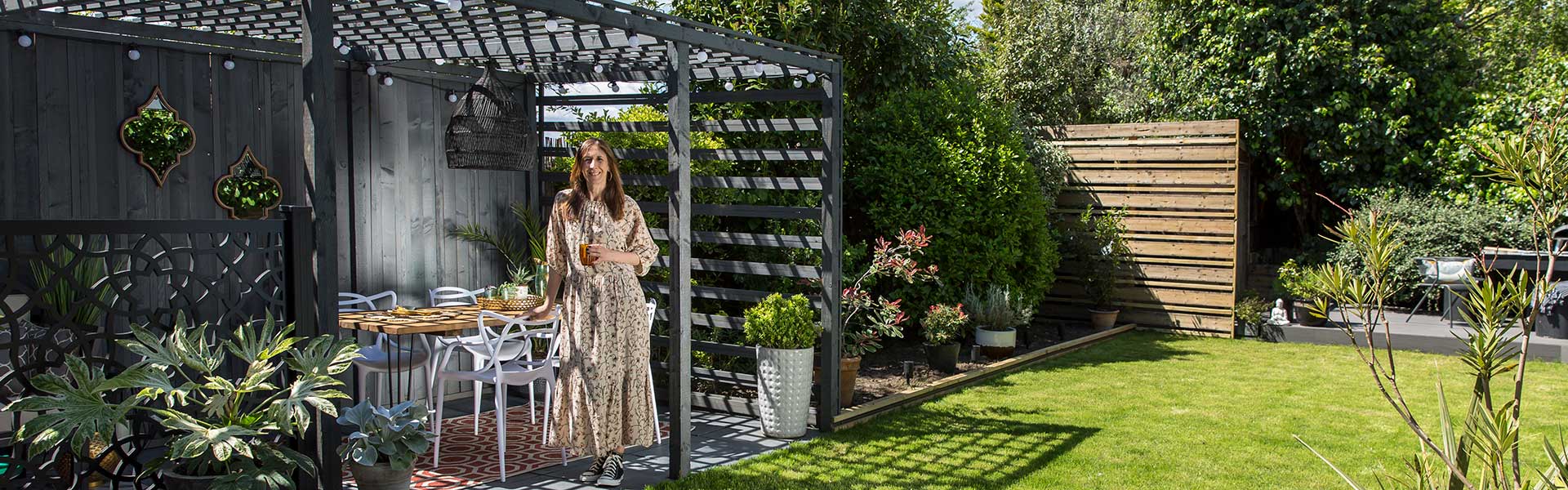 Karen standing in outdoor zoned garden makeover in front of Pergola and plants