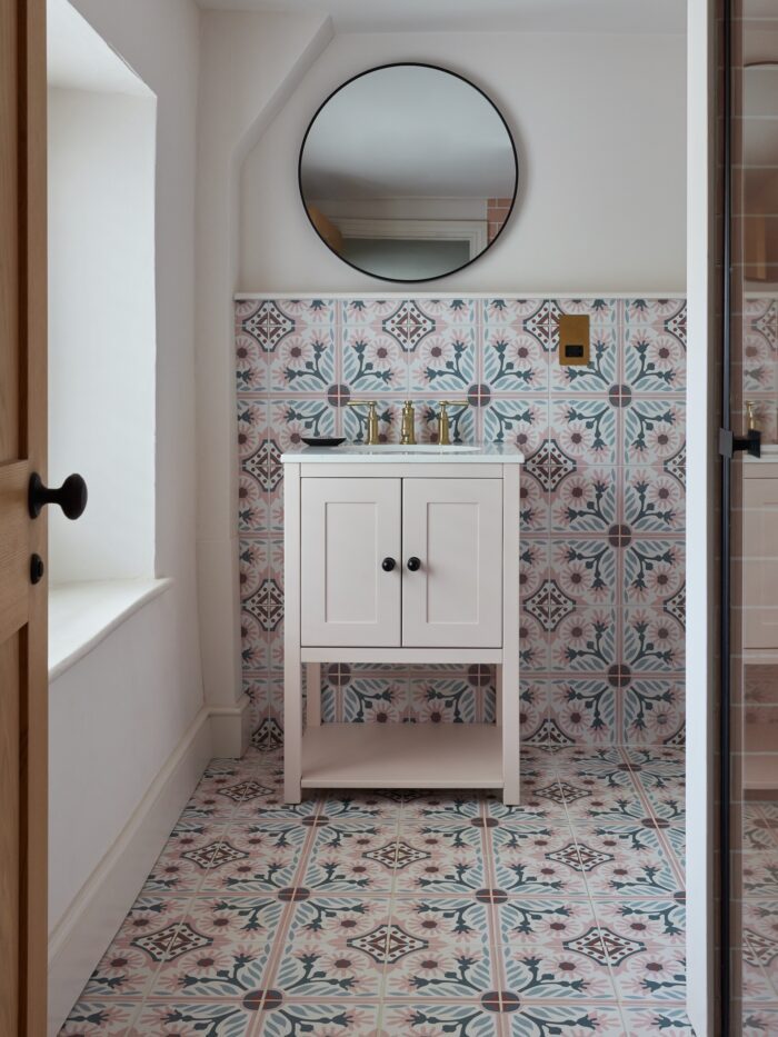 White bathroom with pink patterned wall and floor tiles