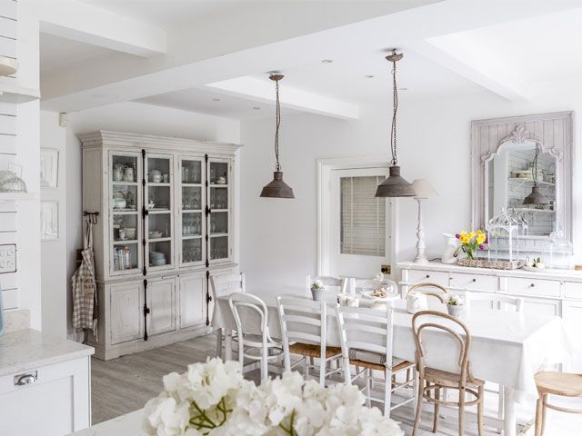 A photo of the Plum Guide house. the Ivory Mansion's white kitchen with white dining table and chairs and a white storage cabinet