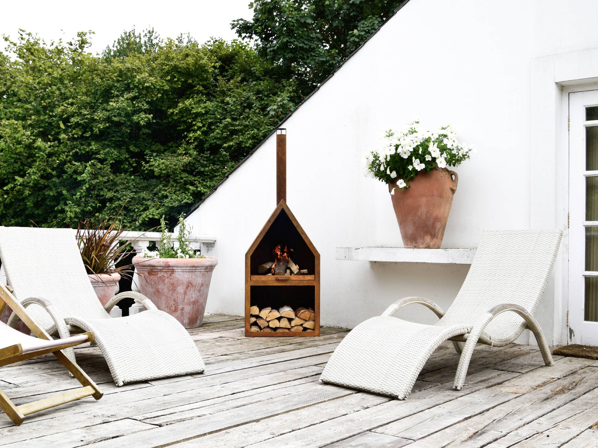 Fire pit with log storage on deck with white loungers
