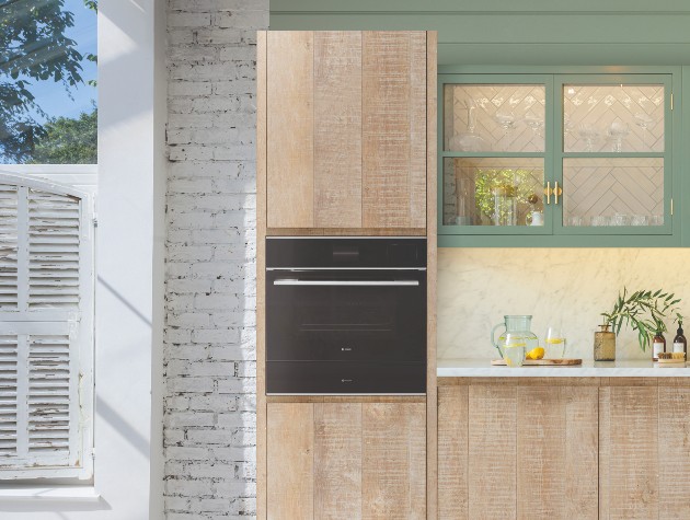 Light contemporary kitchen featuring raw-finished wooden cabinetry and sage green wall cabinet with black Caple Sense Premium C2600 oven