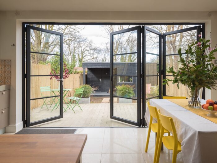 Large bi-fold doors with black aluminium frames opening out onto garden