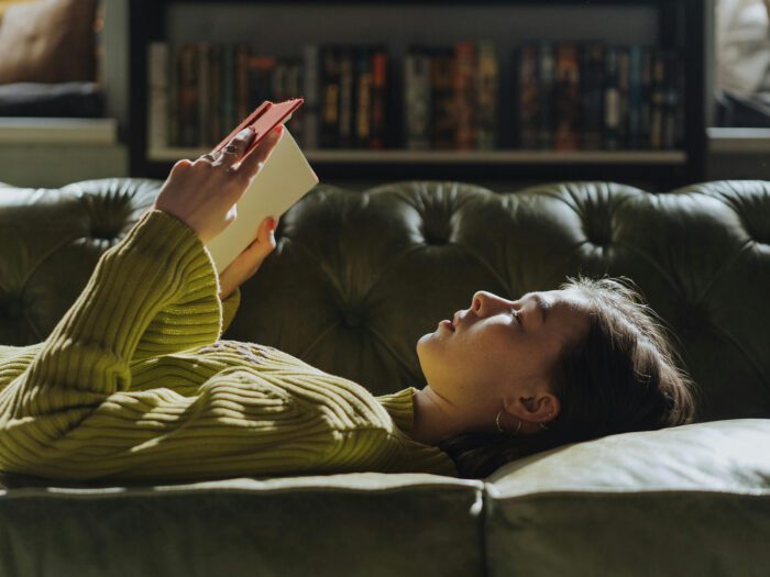 A woman lying on a sofa reading a book 