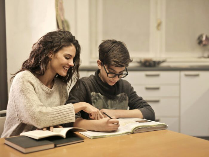 Woman helping boy with homework at the kitchen table