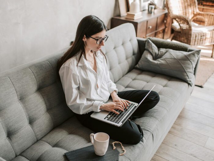 A young woman sitting on a sofa working on a laptop