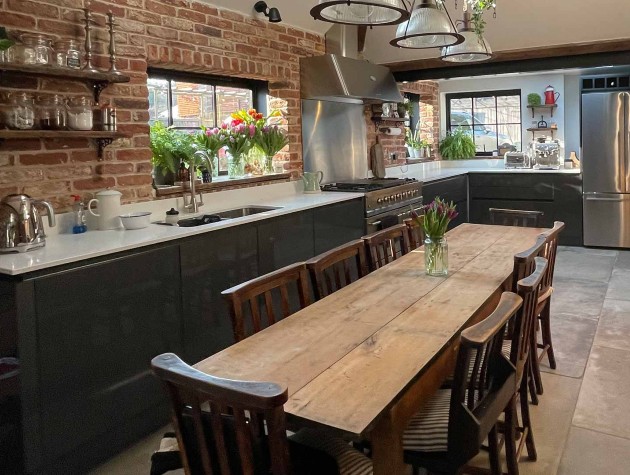 rustic kitchen with exposed-brick walls, Aga cooker and dark blue handleless units with white worktop